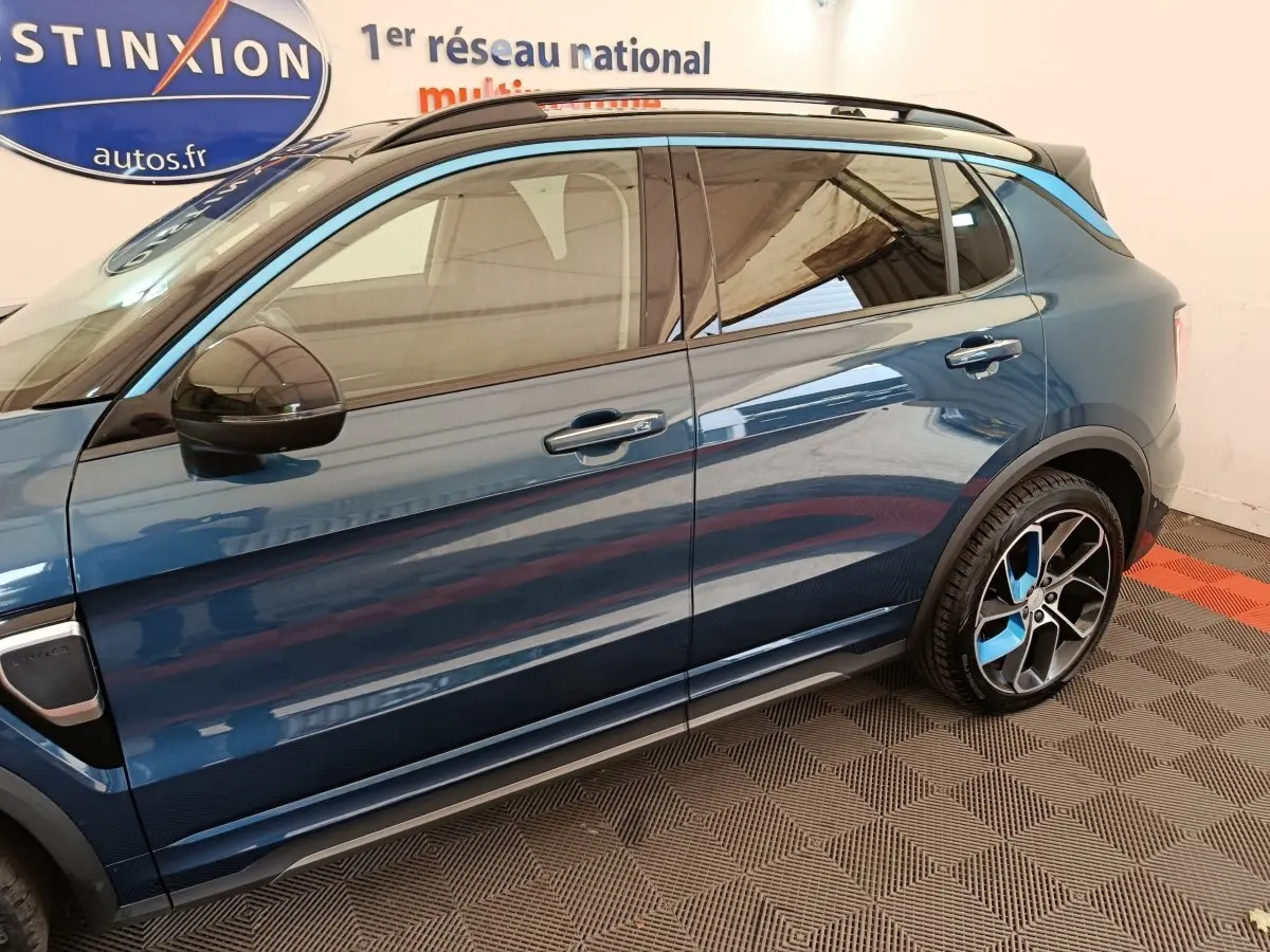 Vue latérale droite du SUV hybride rechargeable Link & Co 01 bleu avec jantes sport bicolores et rétroviseur noir.