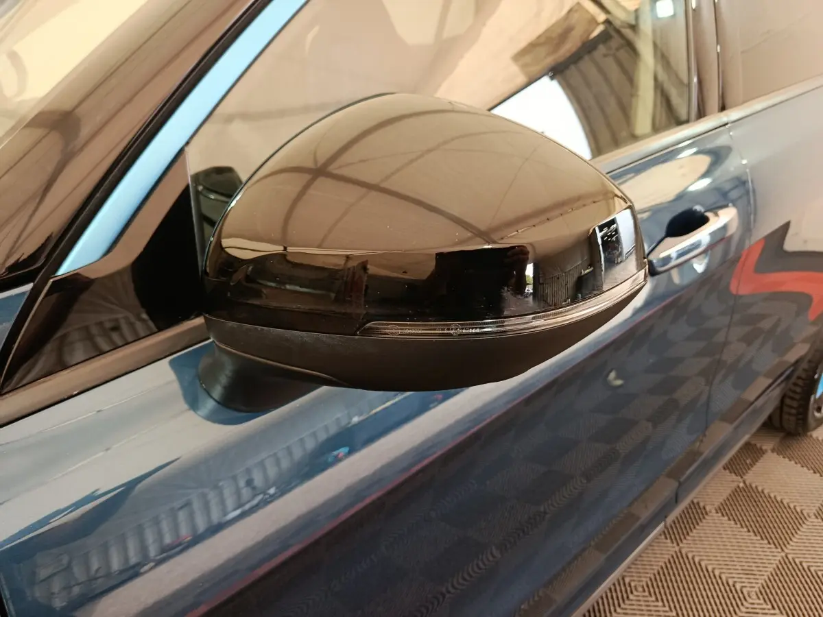 Gros plan sur le rétroviseur droit noir brillant du SUV bleu Link & Co 01 hybride rechargeable, avec poignée de porte visible.