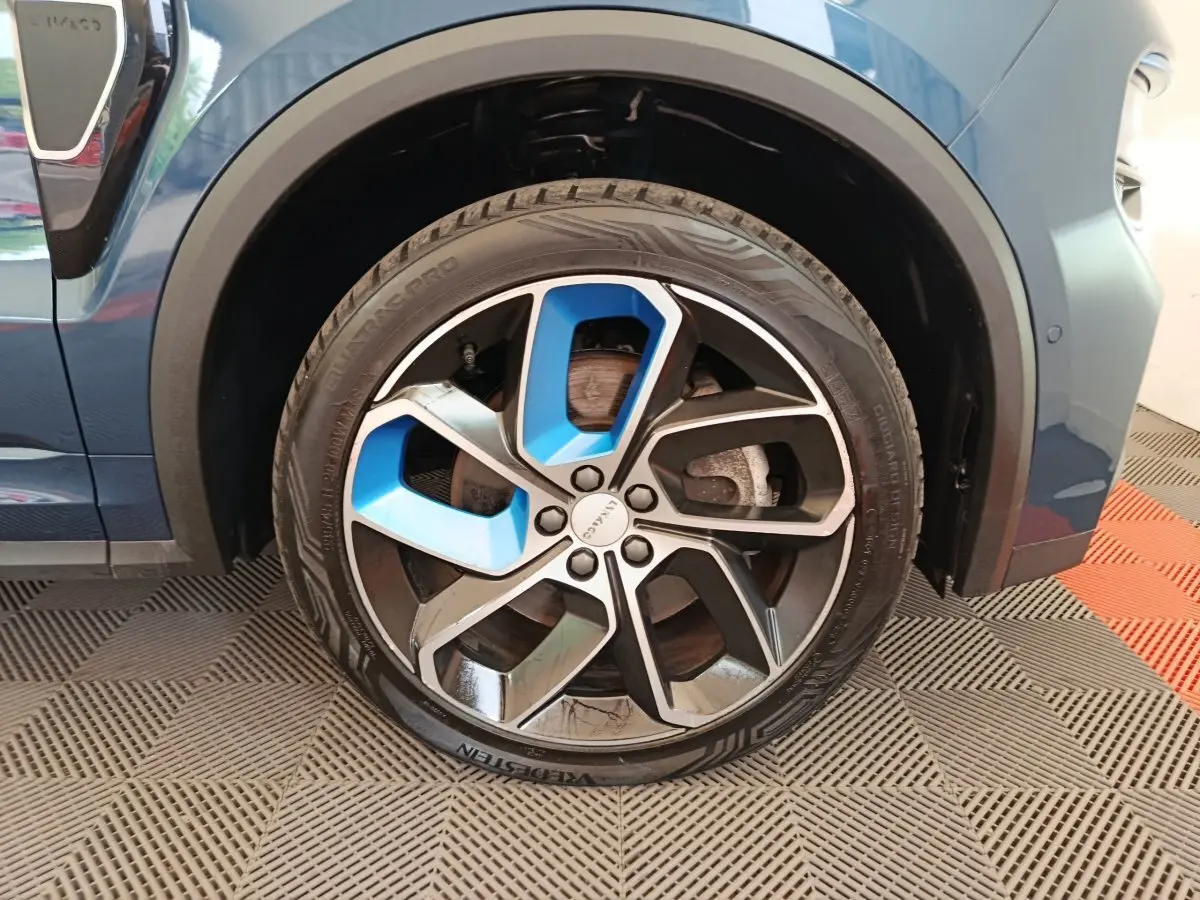 Gros plan sur la roue avant droite bleu et noir du SUV Link & Co 01 hybride rechargeable 2022, avec jante stylisée.