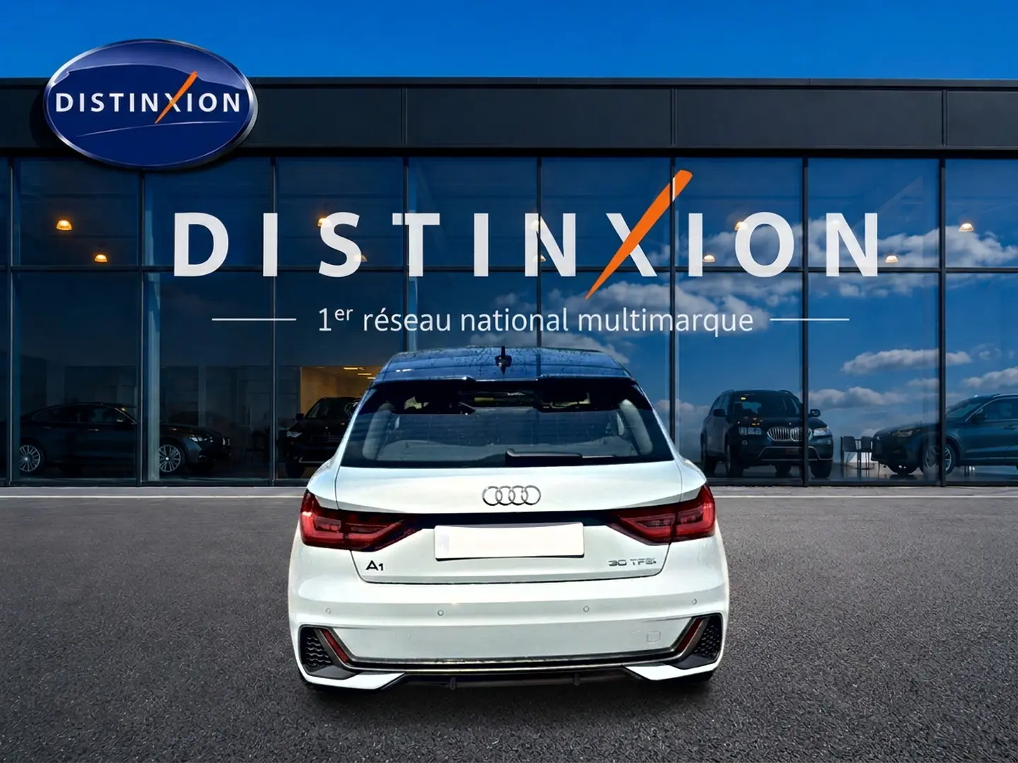 Vue arrière d'une Audi A1 Sportback 30 TFSI gris arrow avec toit noir, stationnée devant une vitrine Distinxion.