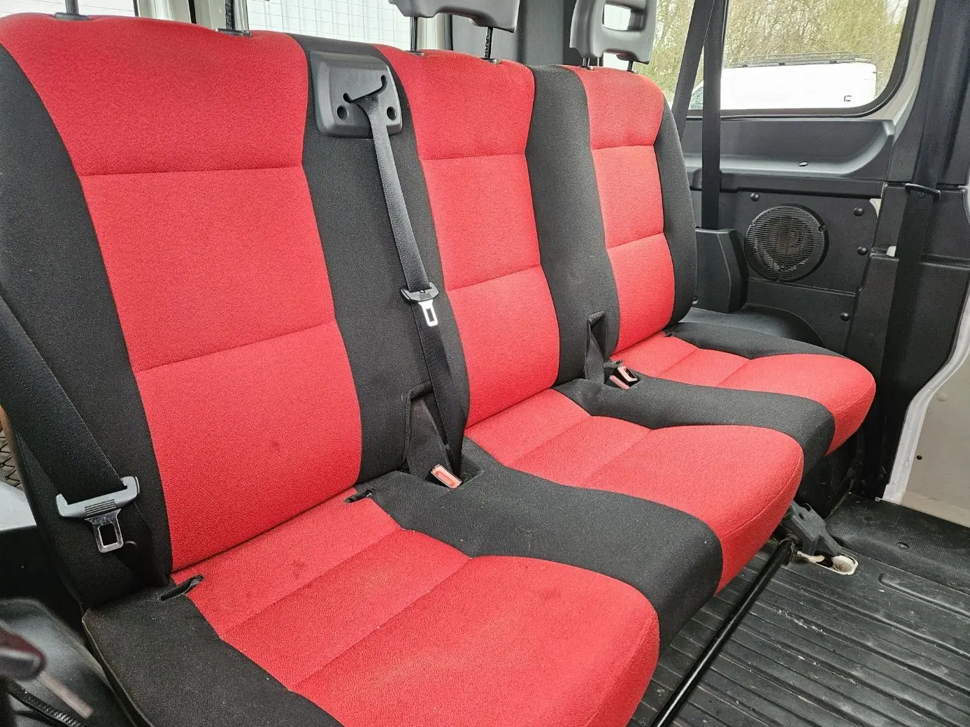 Vue intérieure des sièges arrière rouges et noirs du Fiat Ducato Combi blanc, version 9 places, avec ceintures de sécurité visibles.