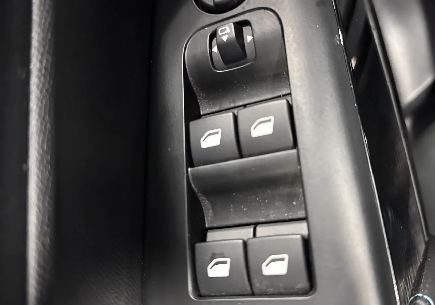 Gros plan sur les commandes de lève-vitres et réglage des rétroviseurs côté conducteur du Citroën C5 Aircross hybride noir 2025.