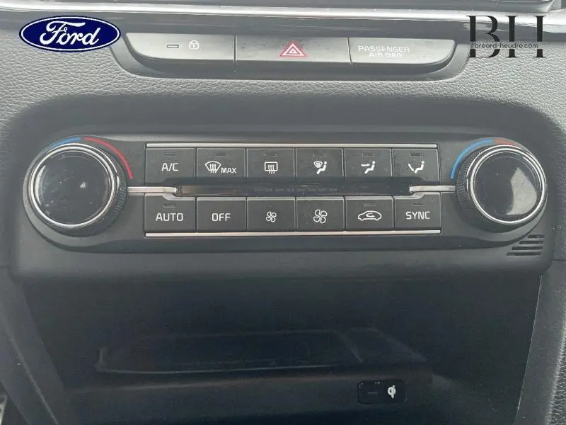 Panneau de commande de climatisation noir avec boutons et molettes, vue frontale intérieure d’une KIA CEE'D 2023.