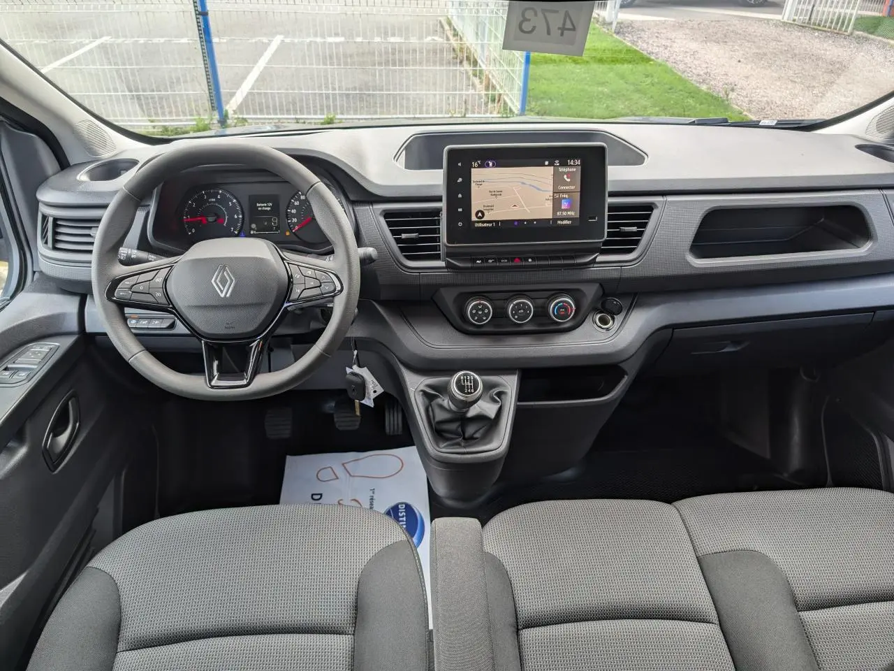 Vue intérieure avant du Renault Trafic Fourgon gris avec tableau de bord moderne et boîte manuelle au centre.