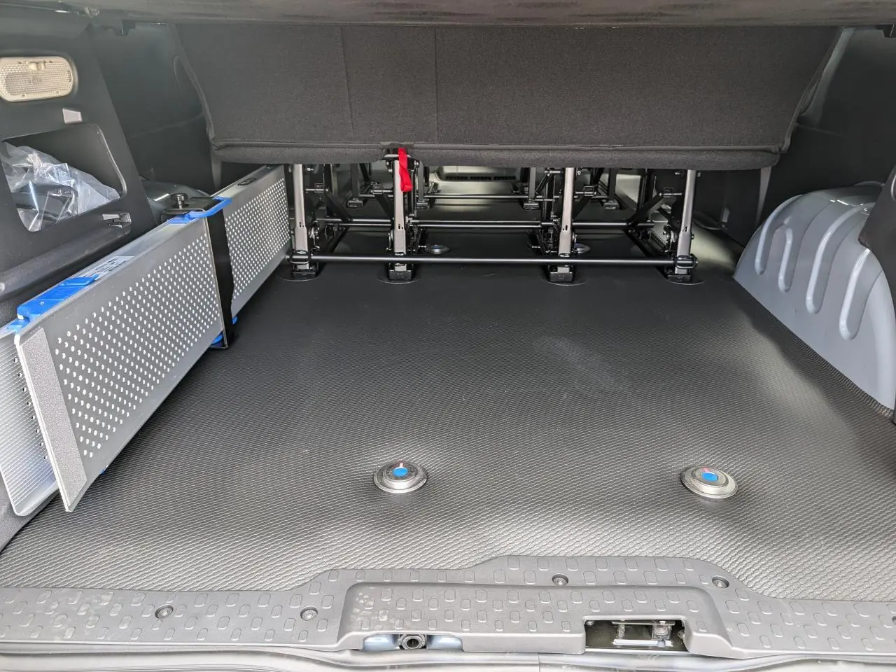 Vue intérieure arrière du Renault Trafic Fourgon gris, montrant le plancher avec rampes amovibles pour accès fauteuil roulant.