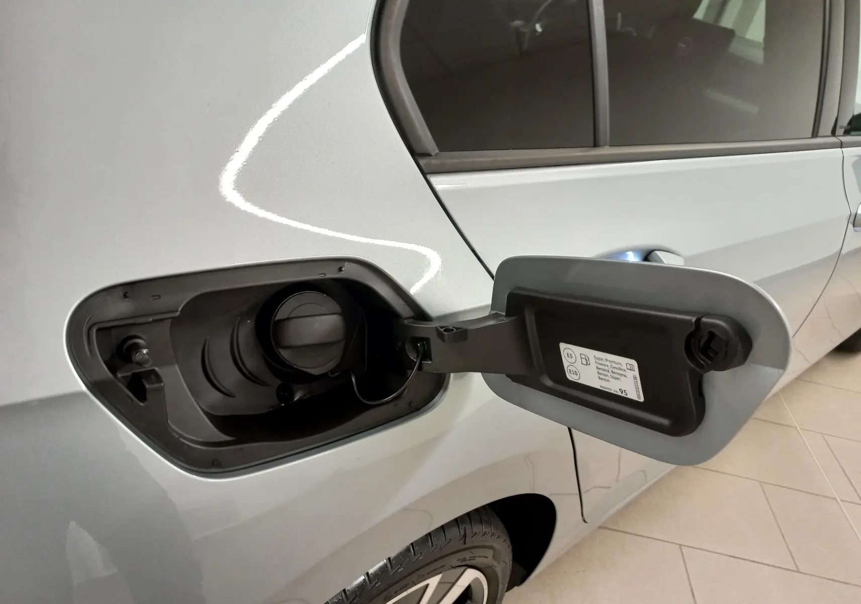 Vue rapprochée de la trappe à carburant ouverte côté gauche d'une Volkswagen Golf 2025 Argent Dolomite avec jantes alliage 18 pouces.