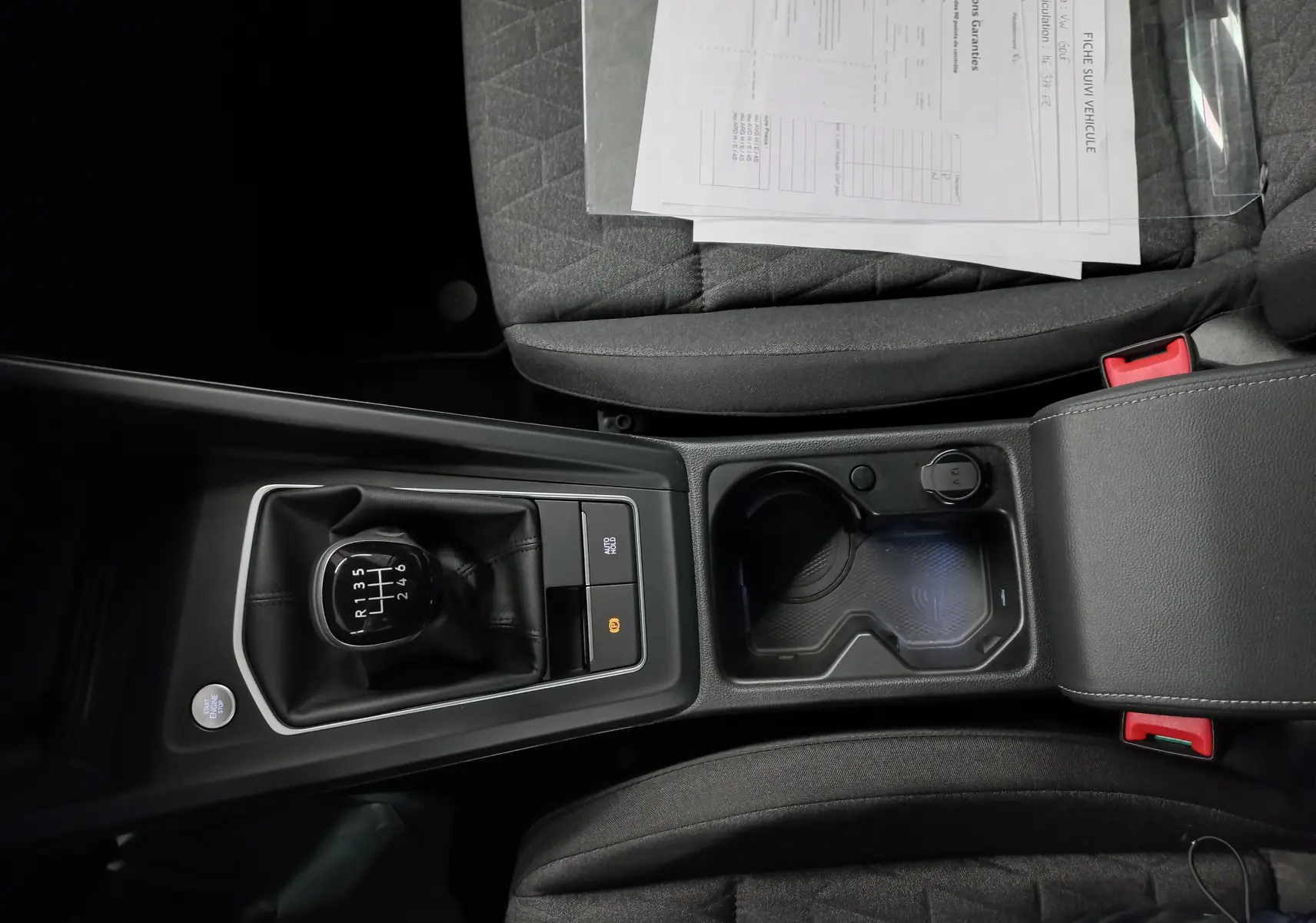 Vue plongeante sur la console centrale de la Volkswagen Golf 1.5 eTSI 116 BVM6, avec levier de vitesses manuel et porte-gobelets.