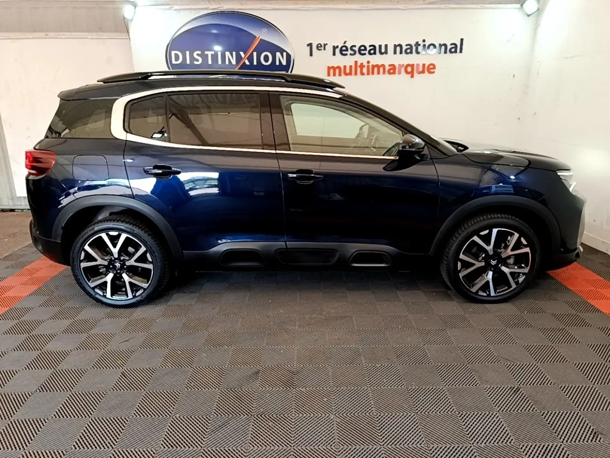 Vue de profil côté gauche d'un Citroën C5 Aircross 2023 bleu foncé avec jantes alliage et toit noir.