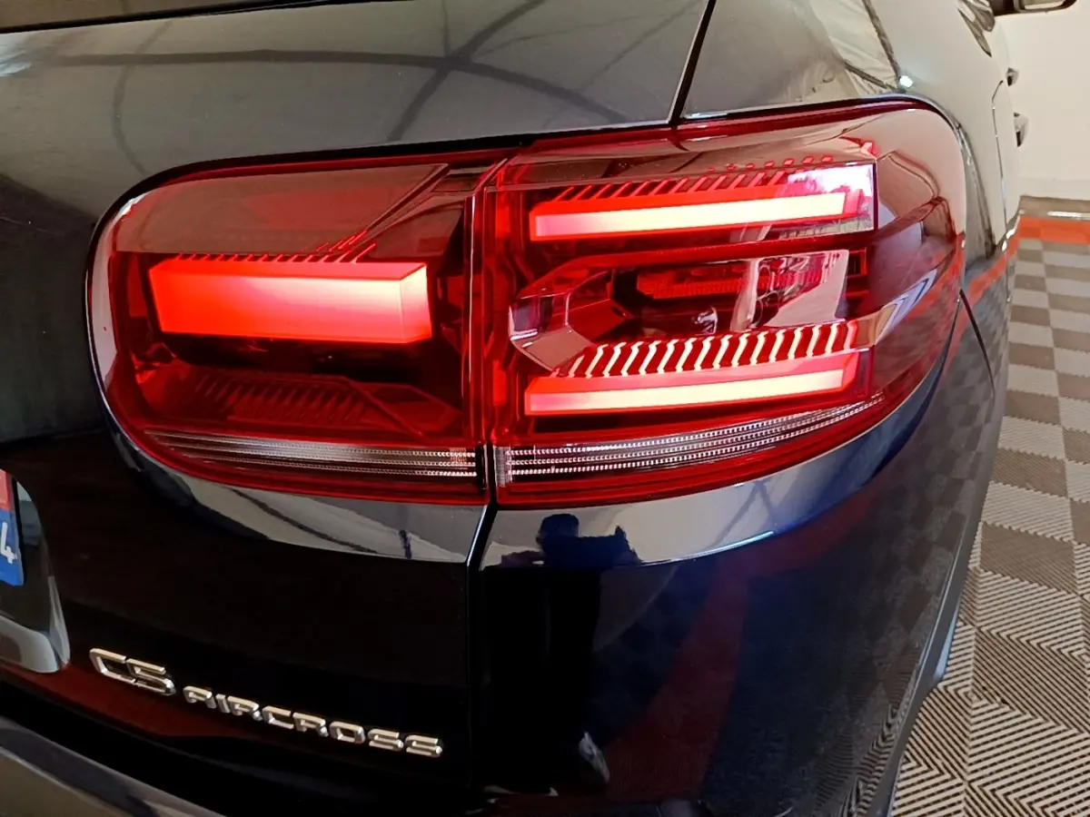 Gros plan sur le feu arrière droit rouge du Citroën C5 Aircross 2023 couleur sombre, avec logo visible sur la malle arrière.