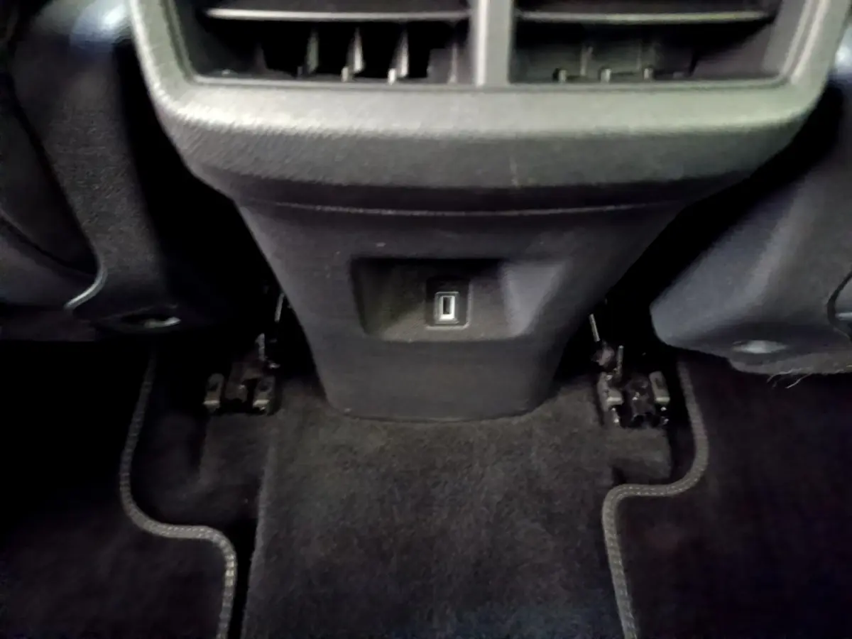 Vue rapprochée de la console arrière noire du Citroën C5 Aircross 2023 avec prise USB et tapis de sol sombre.