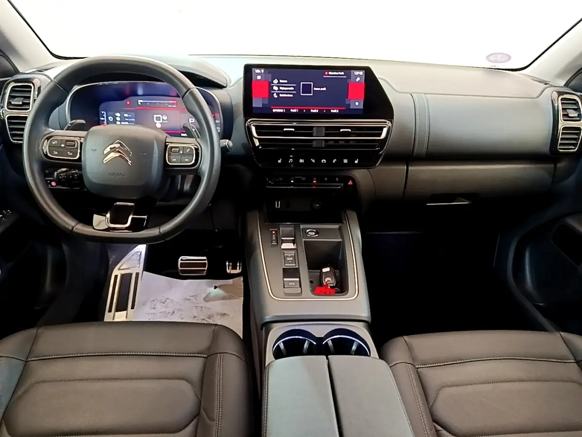 Vue intérieure avant du Citroën C5 Aircross 2023 avec tableau de bord noir et écran tactile central lumineux.