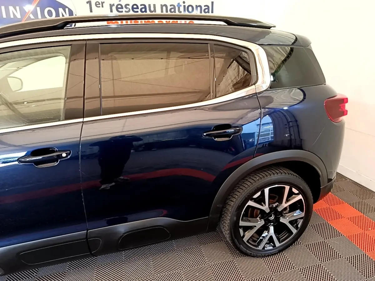 Vue latérale droite du Citroën C5 Aircross bleu foncé avec jantes alliage et protections noires sur bas de caisse.