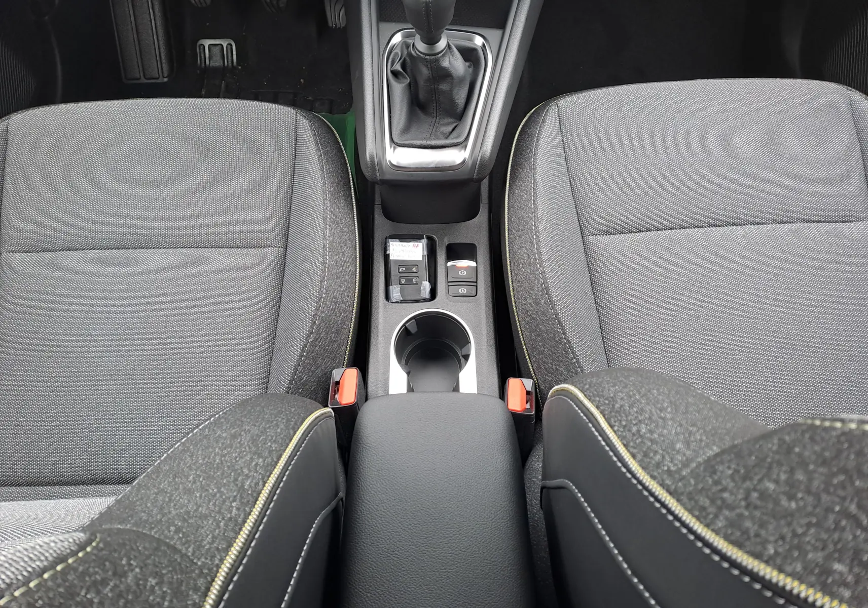 Vue plongeante sur la console centrale et les sièges avant gris foncé avec surpiqûres jaunes du Renault Symbioz 2025.
