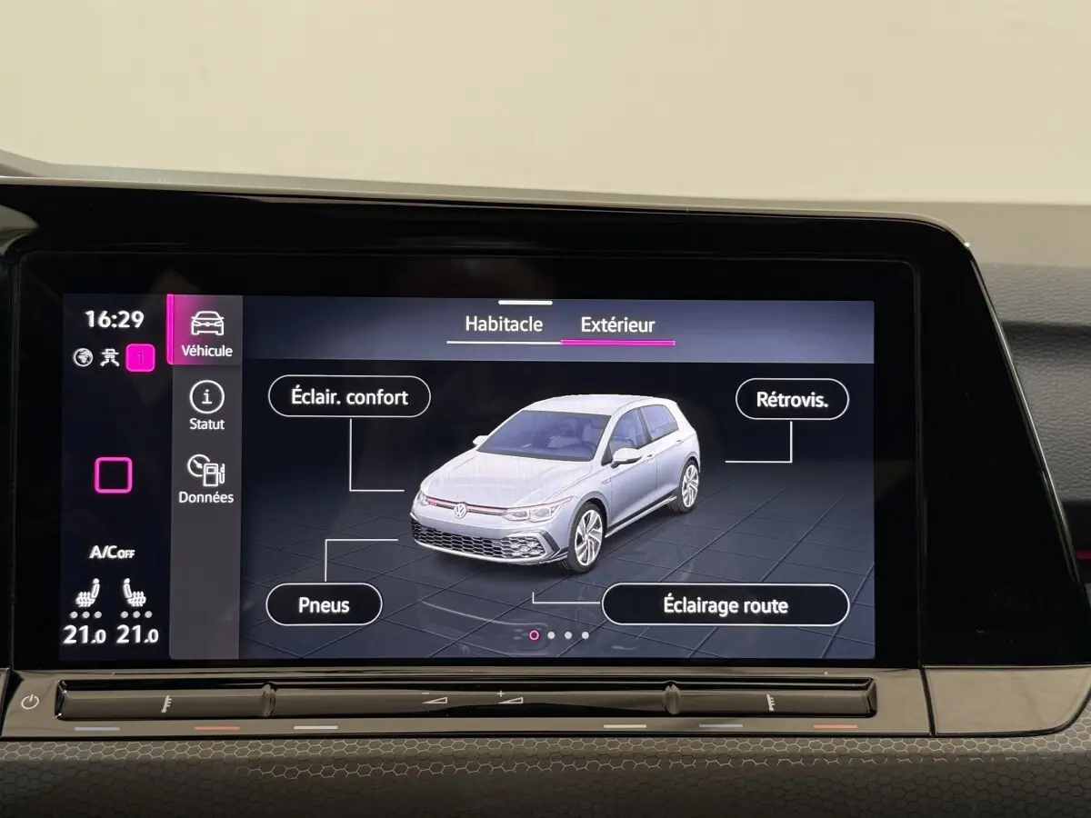 Écran tactile intérieur montrant une Volkswagen Golf vue 3/4 avant en gris clair avec options d'éclairage et pneus.