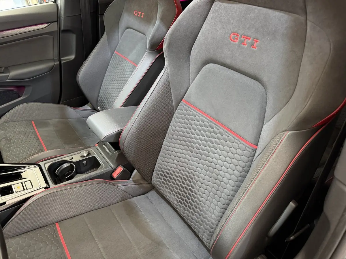 Gros plan sur les sièges avant gris foncé avec surpiqûres rouges et logo GTI brodé dans l’habitacle d’une Volkswagen Golf GTI Clubsport.