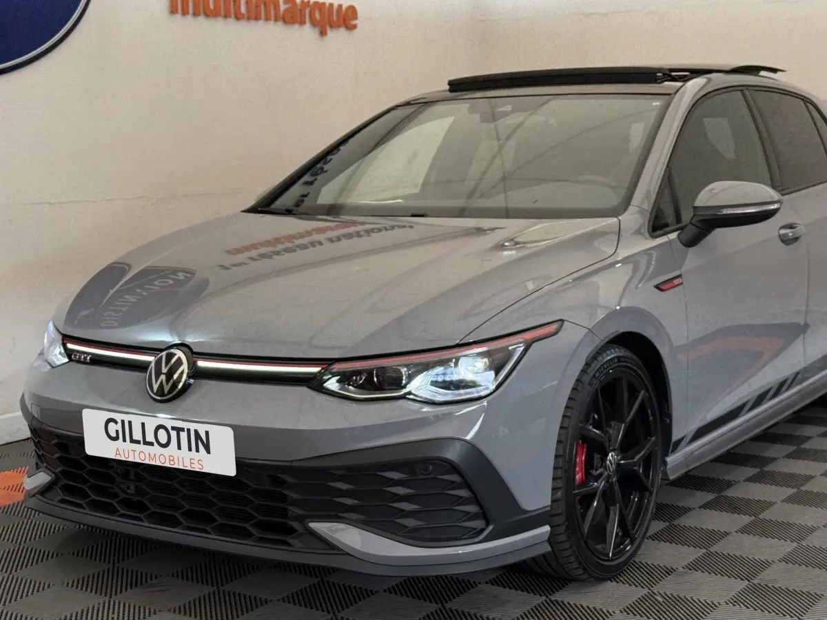 Vue 3/4 avant droite d'une Volkswagen Golf GTI Clubsport gris foncé avec jantes noires et détails rouges.