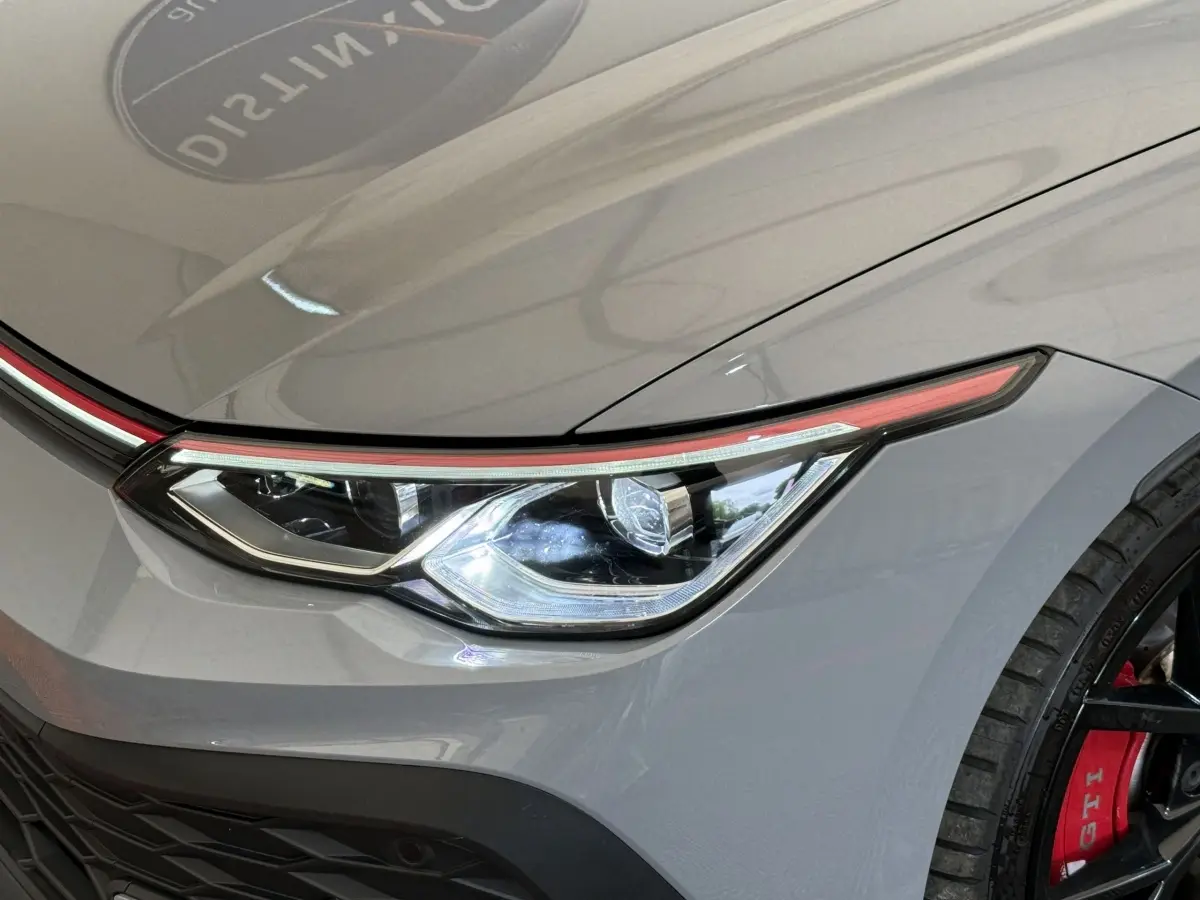 Gros plan sur le phare avant droit gris foncé de la Volkswagen Golf GTI Clubsport avec étrier de frein rouge visible.