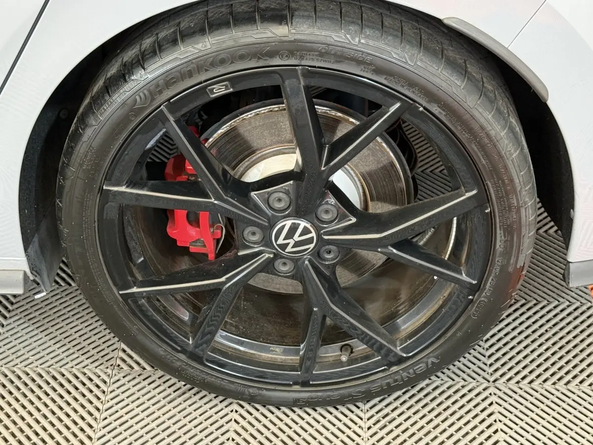 Gros plan sur la roue avant droite noire avec étrier de frein rouge d'une Volkswagen Golf GTI Clubsport gris foncé.