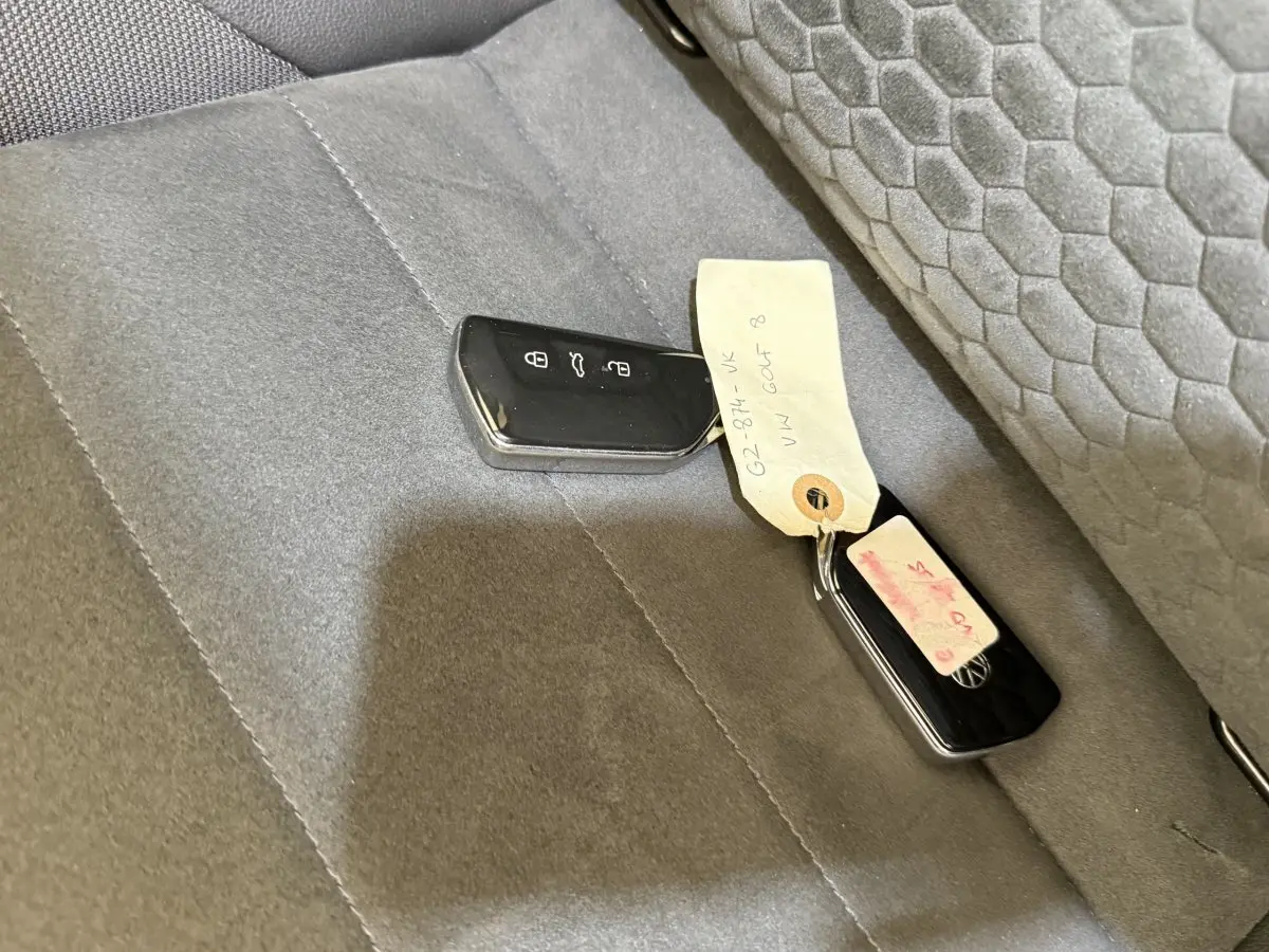 Clé de voiture Volkswagen Golf 2.0 TSI 300 DSG7 GTI Clubsport posée sur siège arrière gris foncé avec tissu texturé.