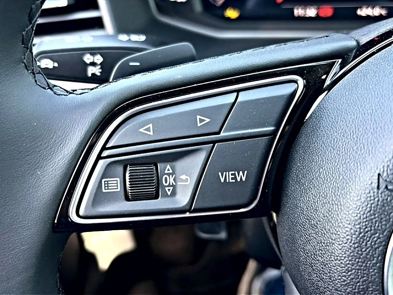Gros plan sur les commandes gauche du volant cuir noir de l'Audi A1 Sportback 2026 avec boutons multifonctions.