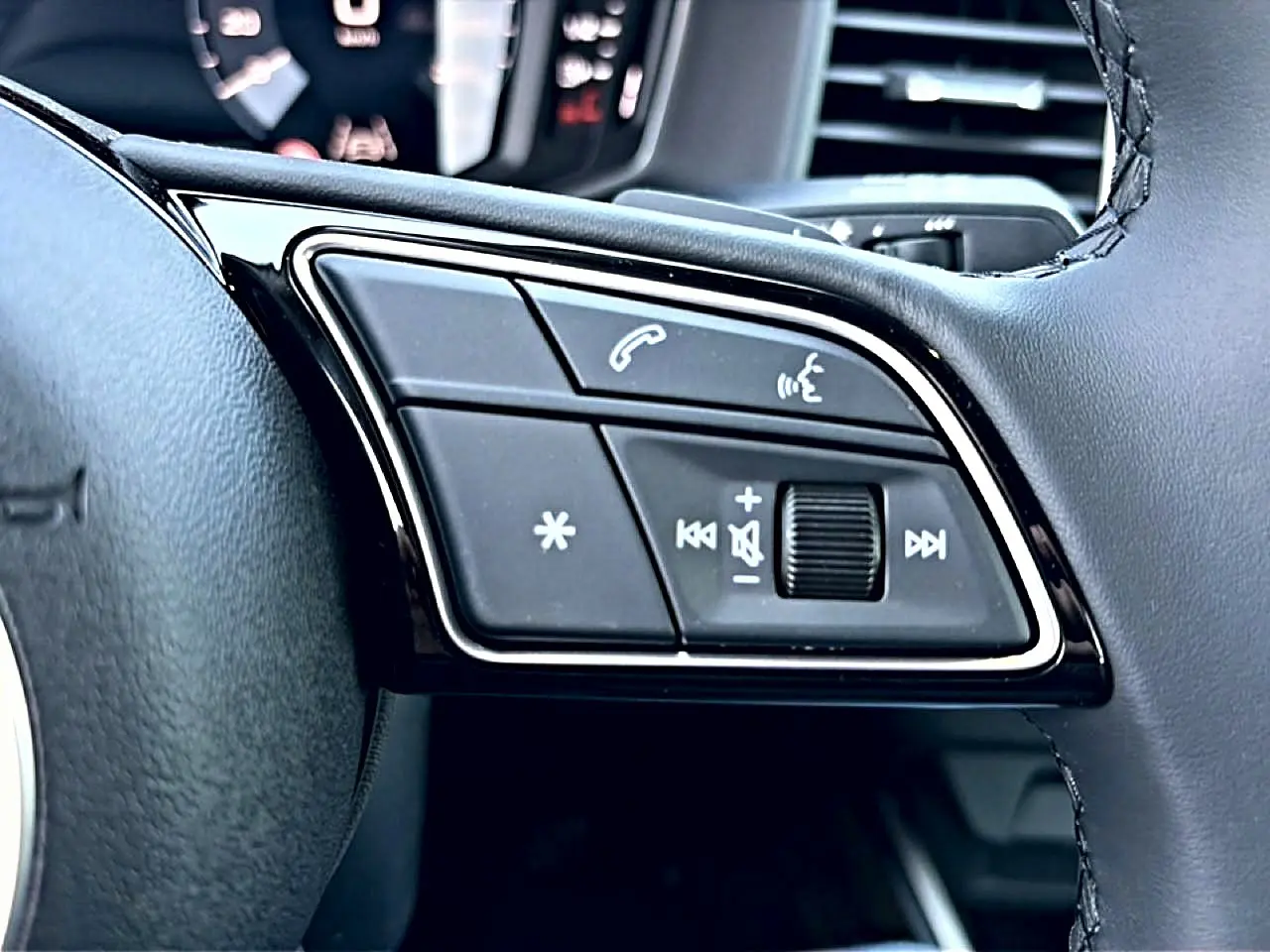 Gros plan sur les commandes multifonctions du volant cuir noir de l'Audi A1 Sportback 2026, avec touches d'appel et volume.