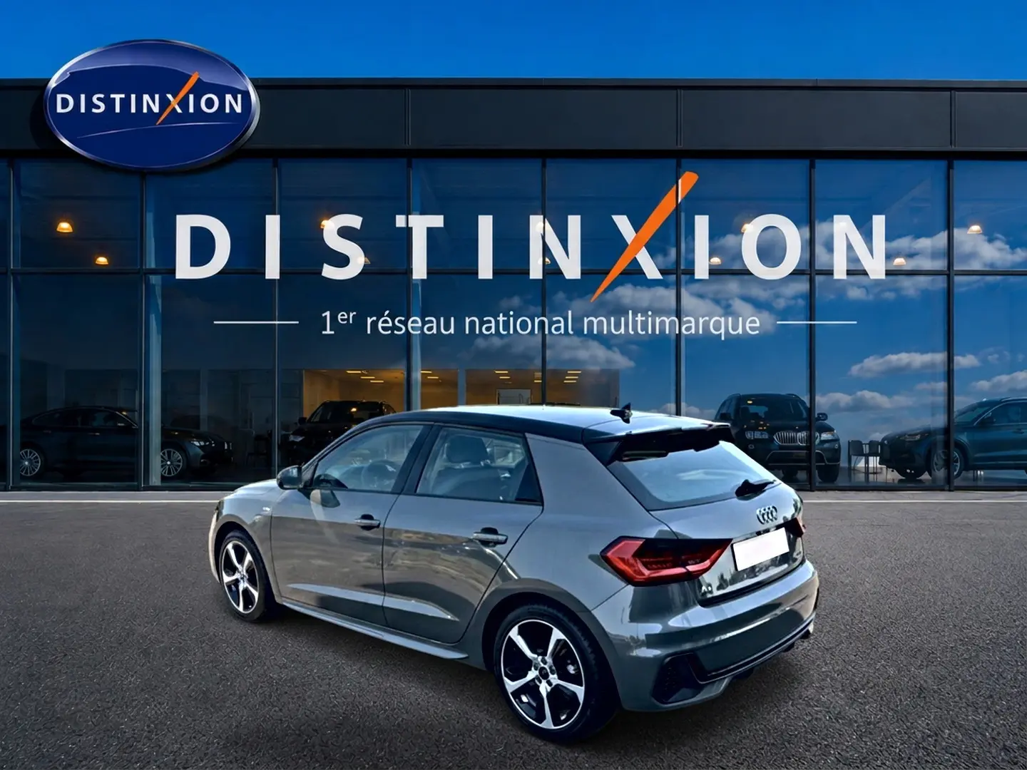 Audi A1 Sportback gris chronos vue 3/4 arrière droit avec jantes alu et toit noir devant showroom Distinxion.