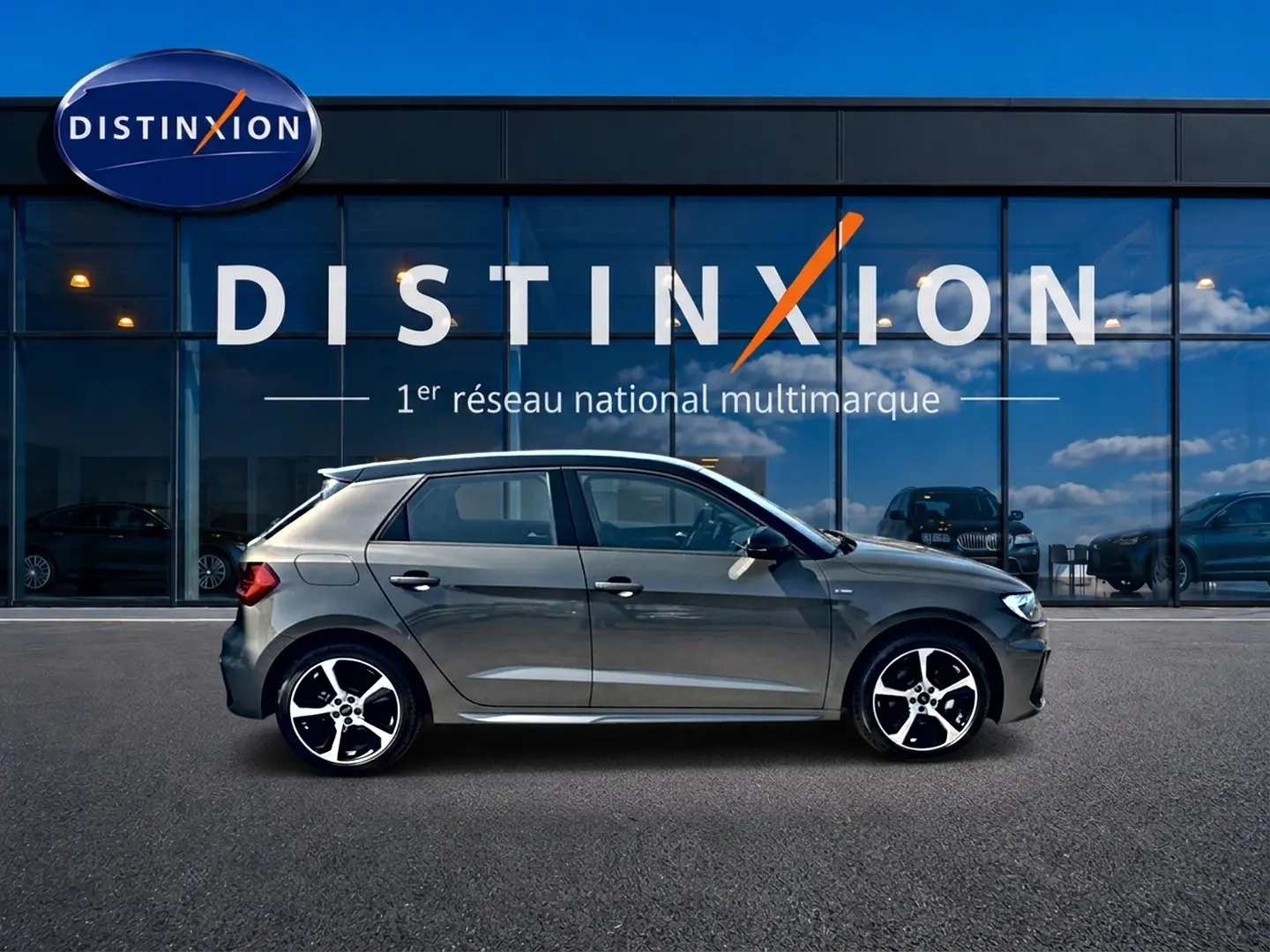 Audi A1 Sportback 30 TFSI gris chronos vue de profil côté gauche devant une vitrine avec logo Distinxion.
