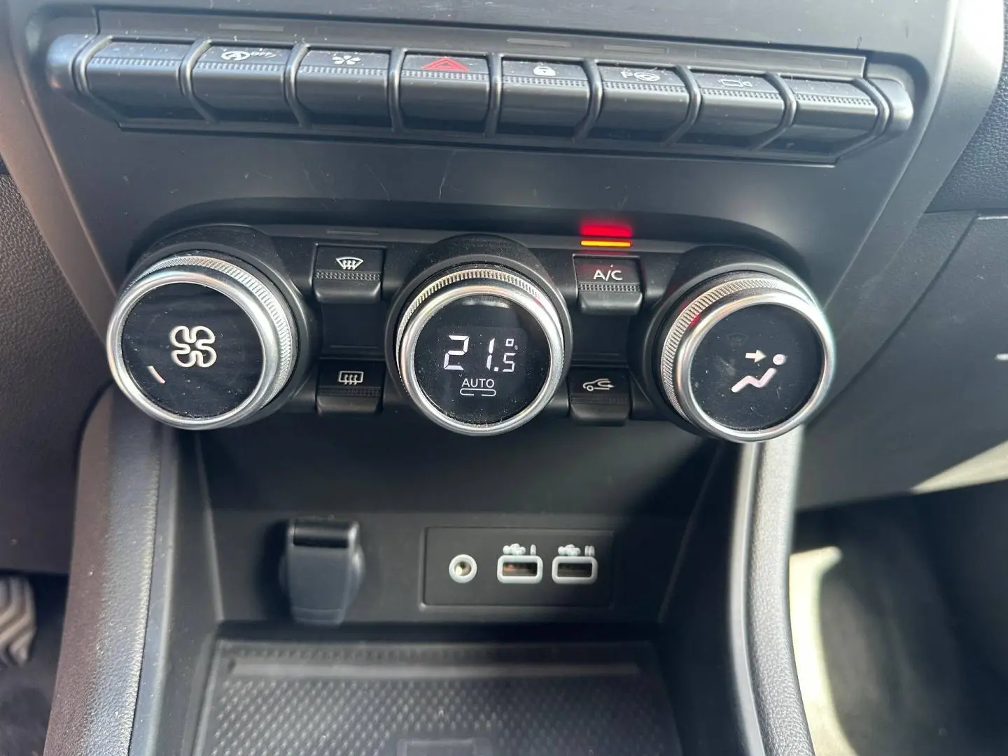 Gros plan sur les commandes de climatisation et les ports USB du Renault Captur 2024 rouge Flamme nacré.