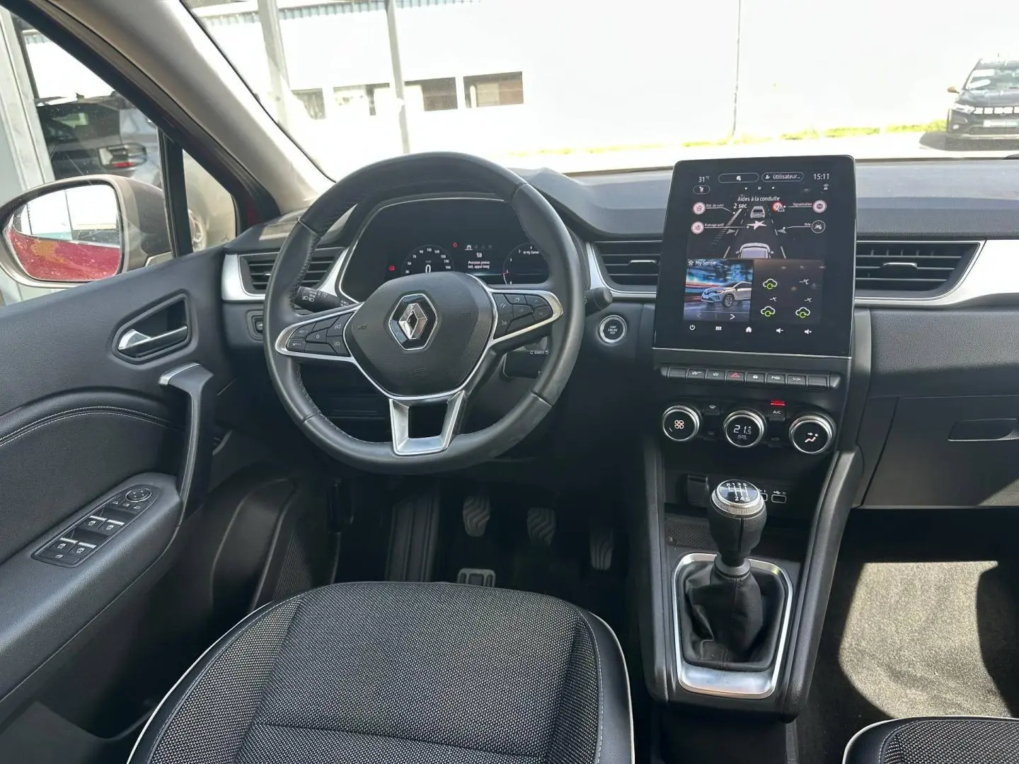 Vue intérieure avant de la Renault Captur 2024, montrant le volant multifonction, la boîte manuelle et l’écran tactile central.
