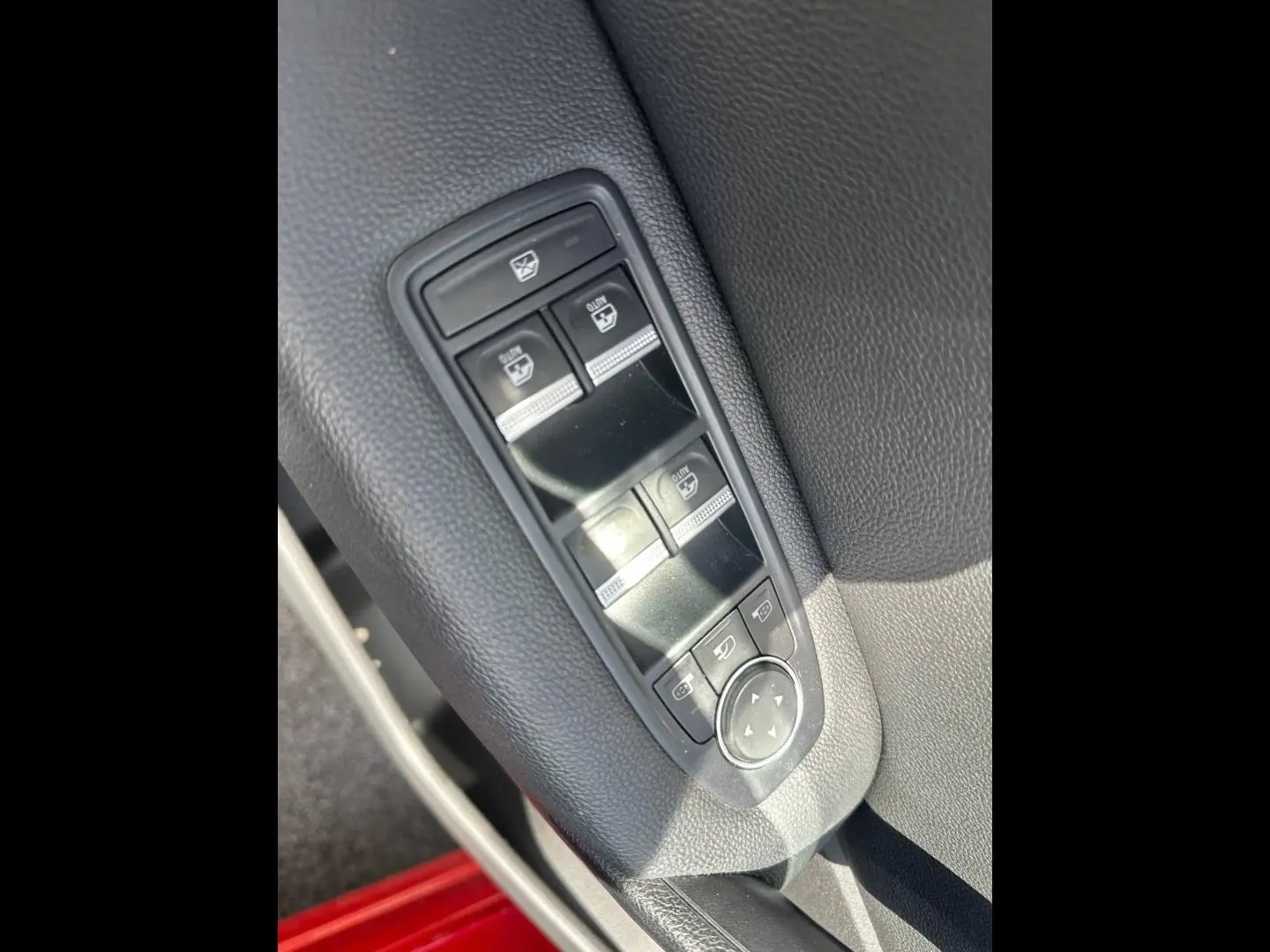 Gros plan sur les commandes de lève-vitres et réglage des rétroviseurs côté conducteur du Renault Captur Rouge Flamme nacré.