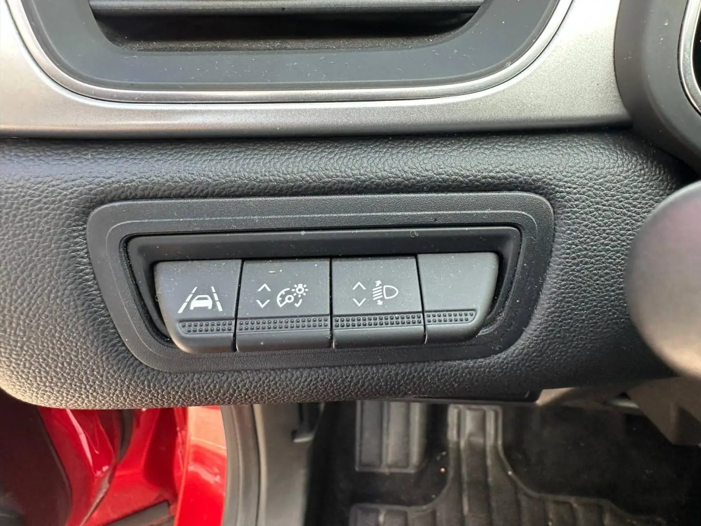 Gros plan sur les boutons de réglage d'assistance et éclairage du tableau de bord d'un Renault Captur Rouge Flamme nacré.