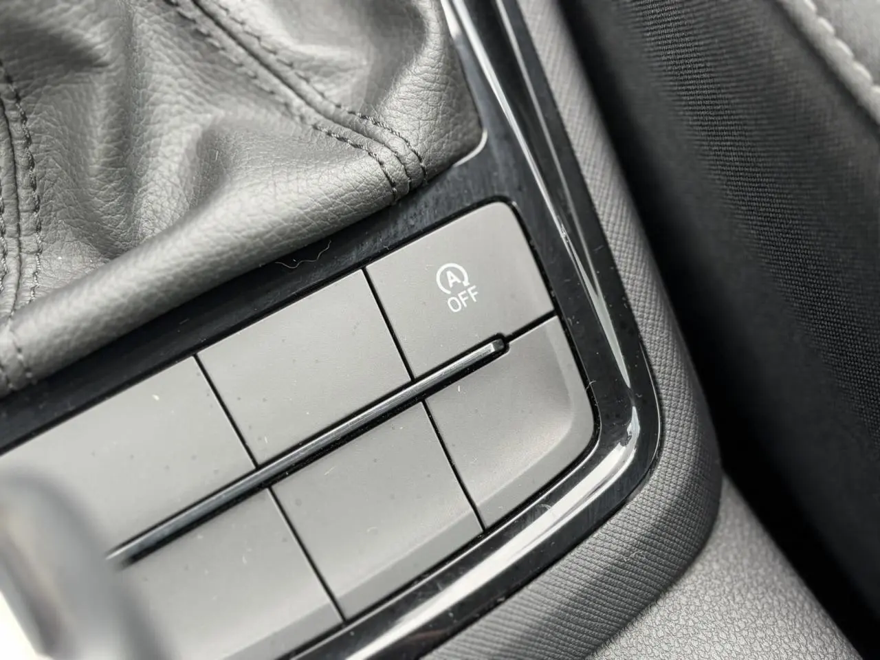Gros plan sur le bouton de désactivation du système start-stop dans l'accoudoir central d'une Skoda Scala 2024.