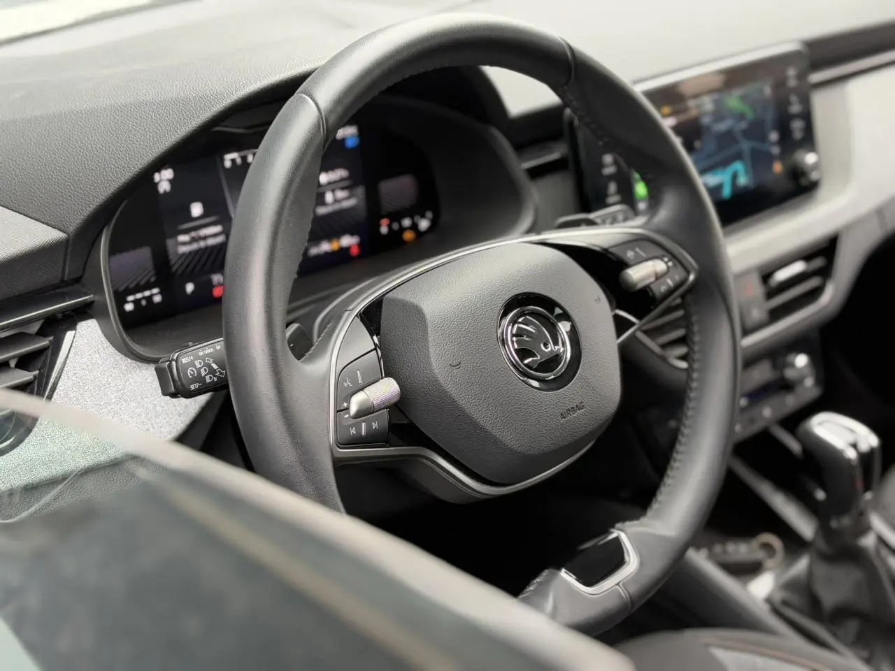 Gros plan sur le volant cuir multifonctions de la Skoda Scala 2024, avec tableau de bord digital en arrière-plan.