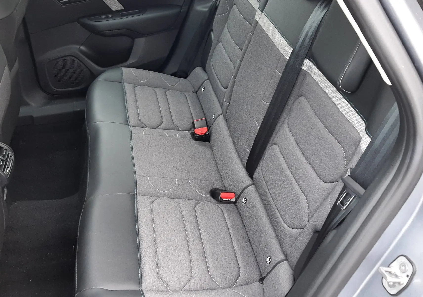 Vue intérieure côté arrière droit montrant la banquette bi-matière gris tissu et cuir du Citroën C4 Hybrid 136 e-DSC6 Plus 2024.