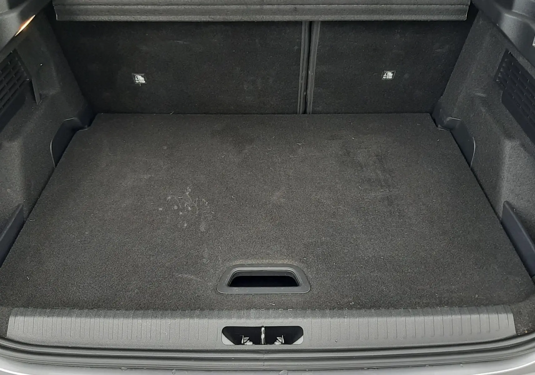 Coffre ouvert vu de l'arrière d'une Citroën C4 Hybrid 136 gris acier, montrant un espace de chargement propre et spacieux.