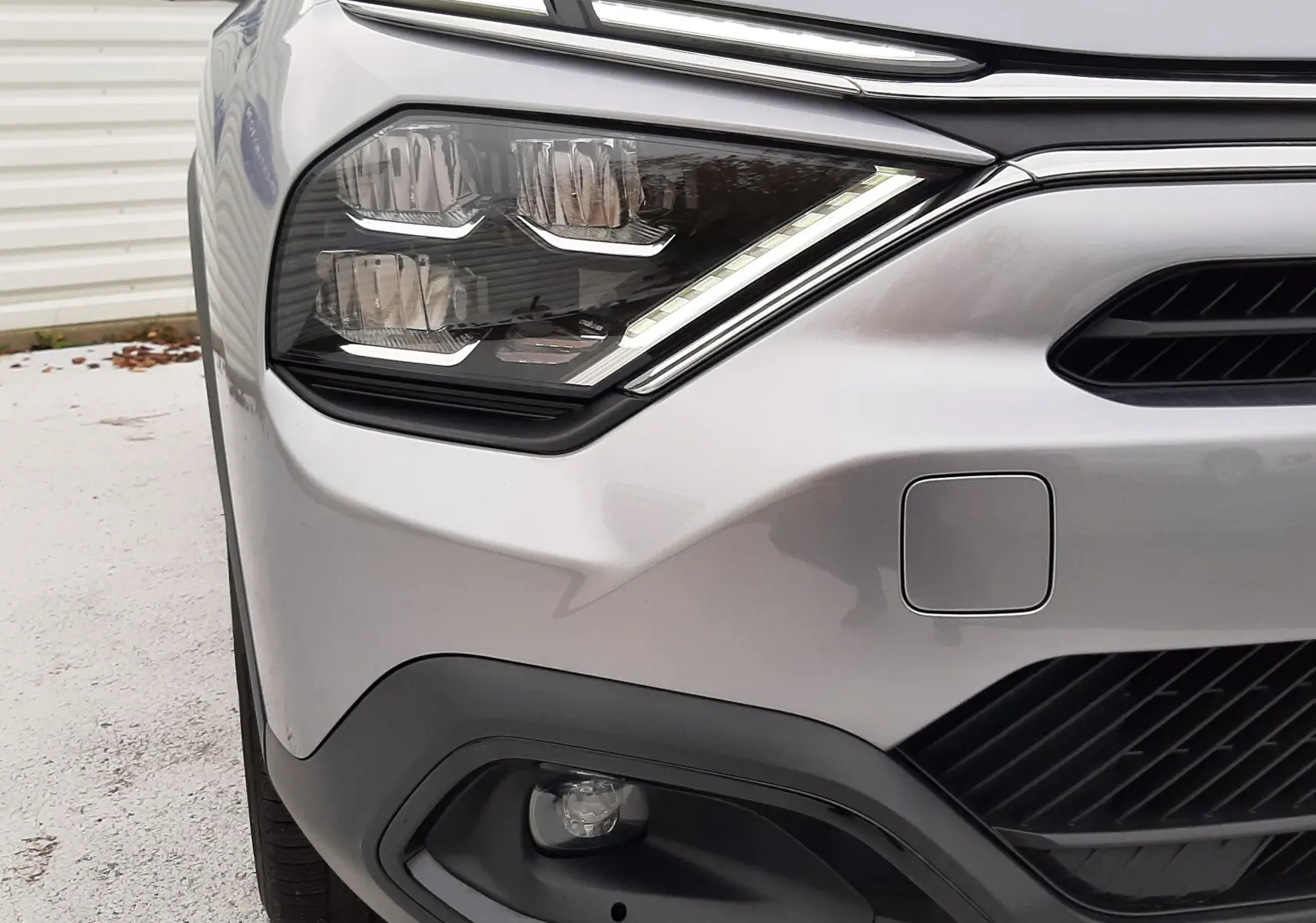 Gros plan sur l'avant gauche de la Citroën C4 gris acier 2024, mettant en valeur ses phares LED et la calandre noire.