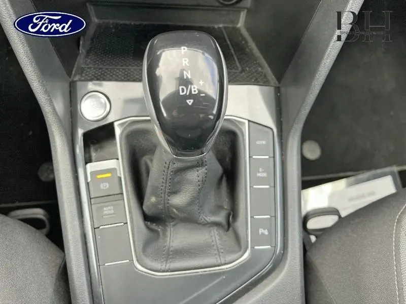 Gros plan sur le levier de vitesse automatique noir du Volkswagen Tiguan 1.4 eHybrid, entouré de boutons de contrôle.