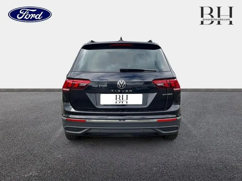 Vue arrière d'un Volkswagen Tiguan 1.4 eHybrid noir intense nacré avec feux LED et logo distinctif au centre.