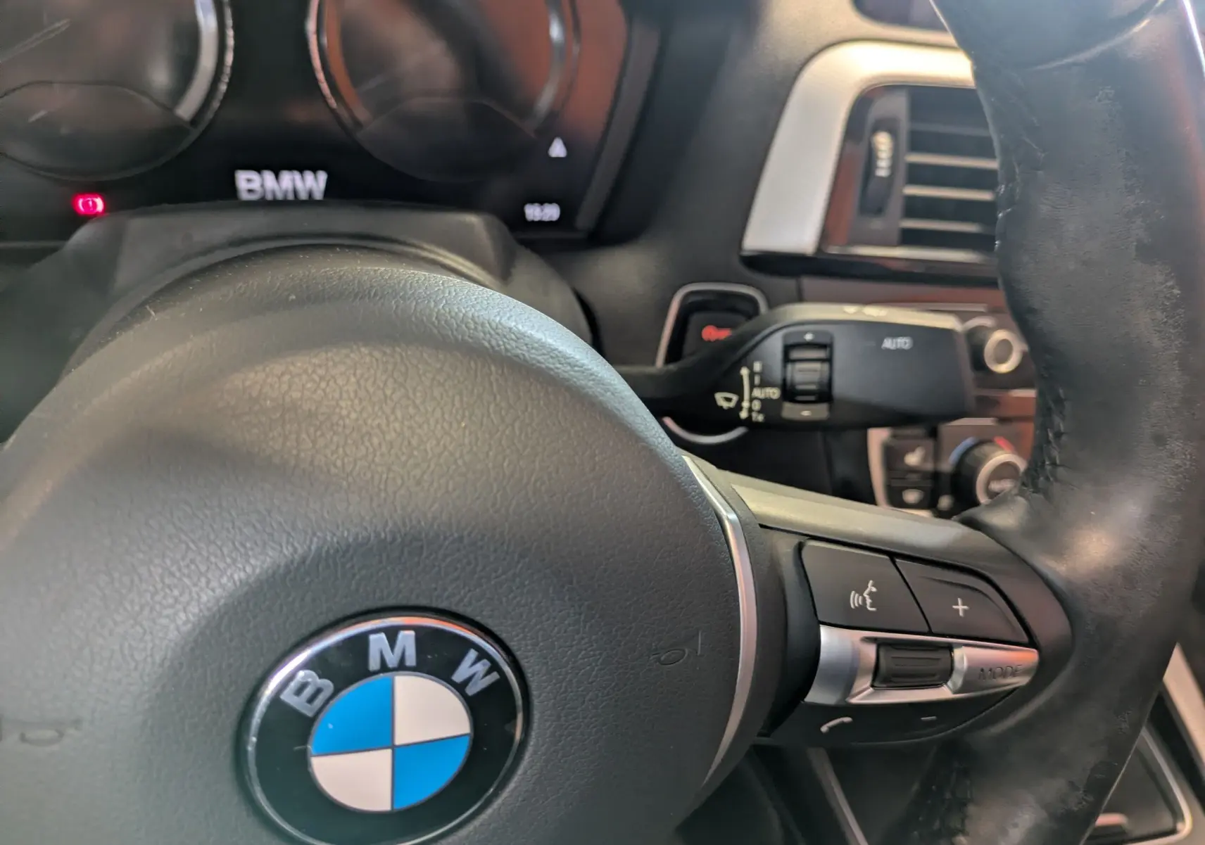 Gros plan sur le volant en cuir noir d'une BMW Série 2 Cabriolet 218dA, avec commandes intégrées visibles à droite.