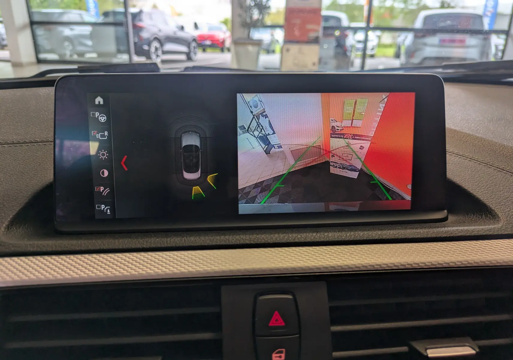 Vue intérieure du tableau de bord de la BMW Série 2 Cabriolet noire, avec l'écran affichant la caméra de recul et l'aide au stationnement.