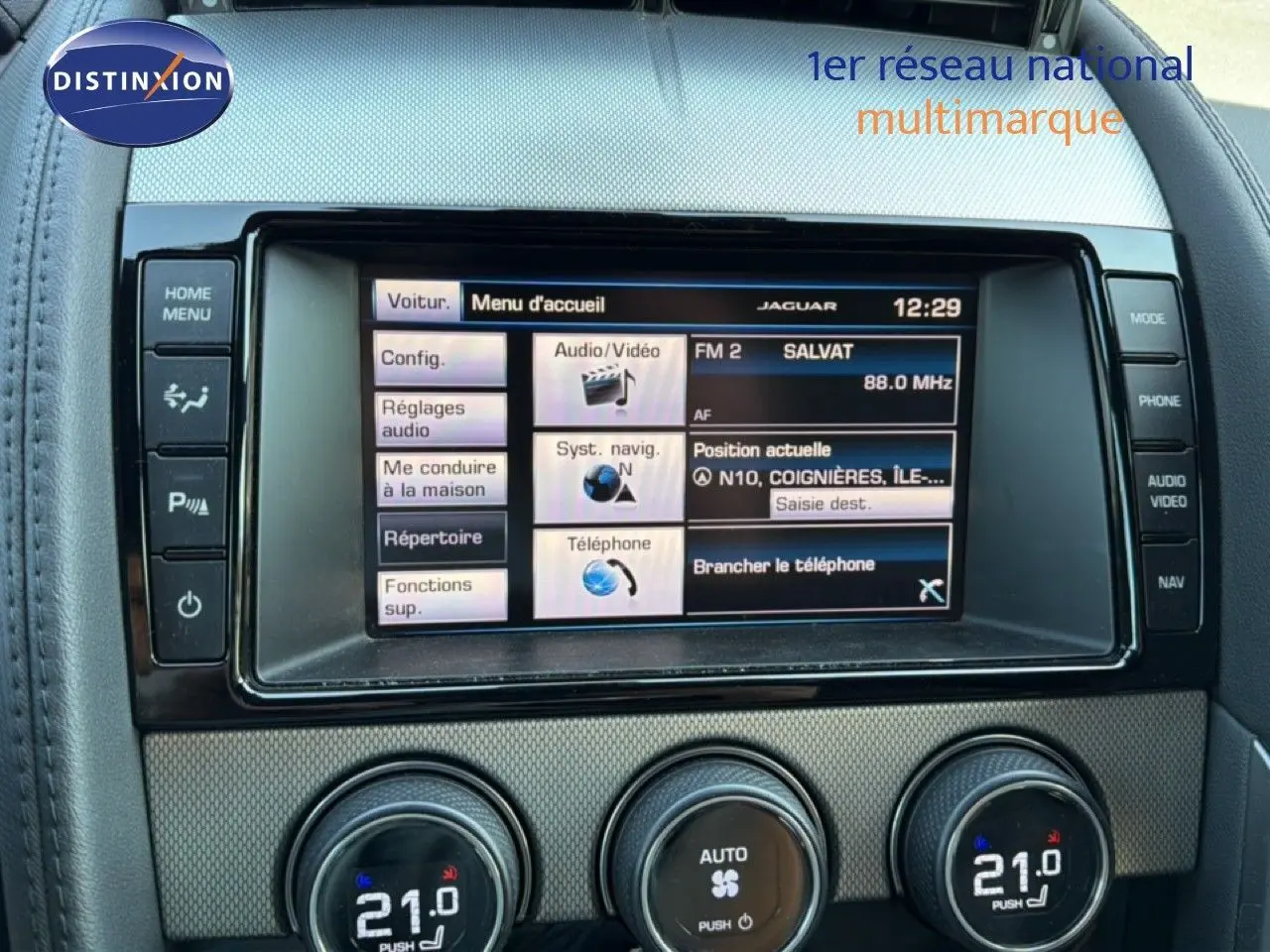 Gros plan sur l’écran tactile central et les commandes de climatisation d’une Jaguar F-TYPE gris, intérieur cuir noir.