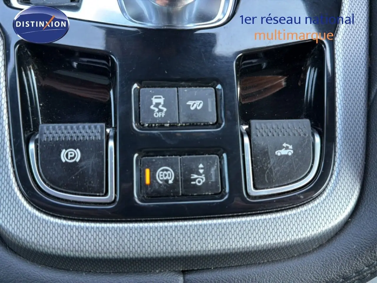 Gros plan sur les commandes centrales noires et argentées du tableau de bord d'une Jaguar F-TYPE gris 2013.