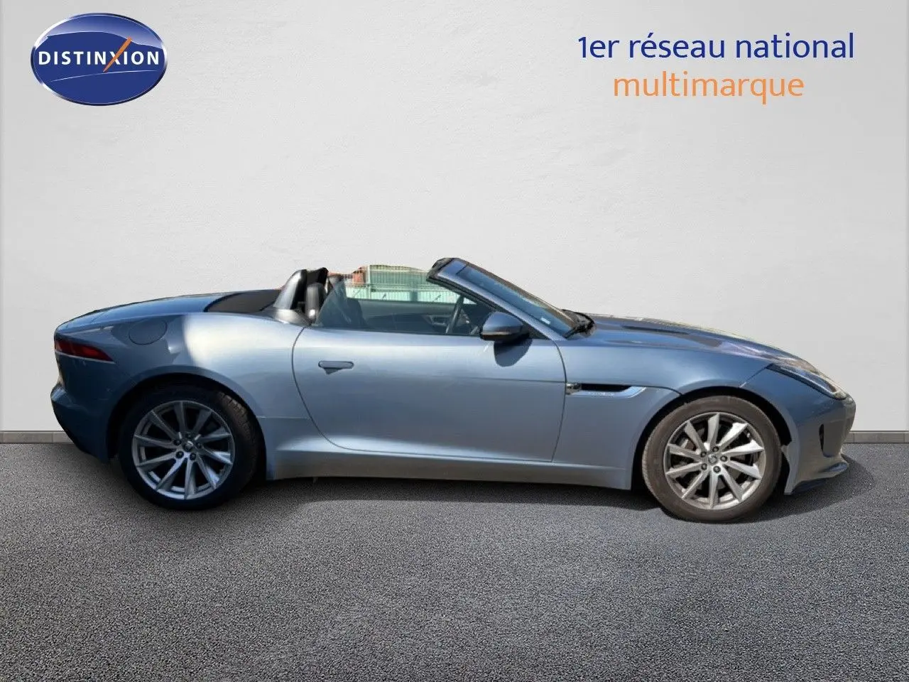 Jaguar F-TYPE cabriolet gris vue de profil côté gauche, toit ouvert et jantes alliage visibles.