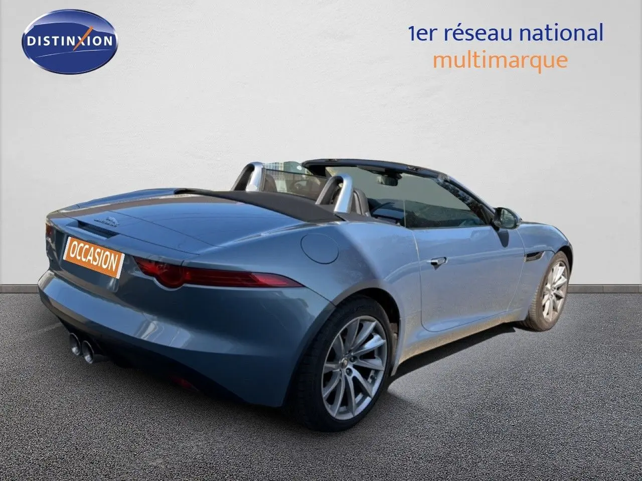 Jaguar F-TYPE cabriolet gris vue 3/4 arrière droit, jantes alliage et double sortie d’échappement visible.