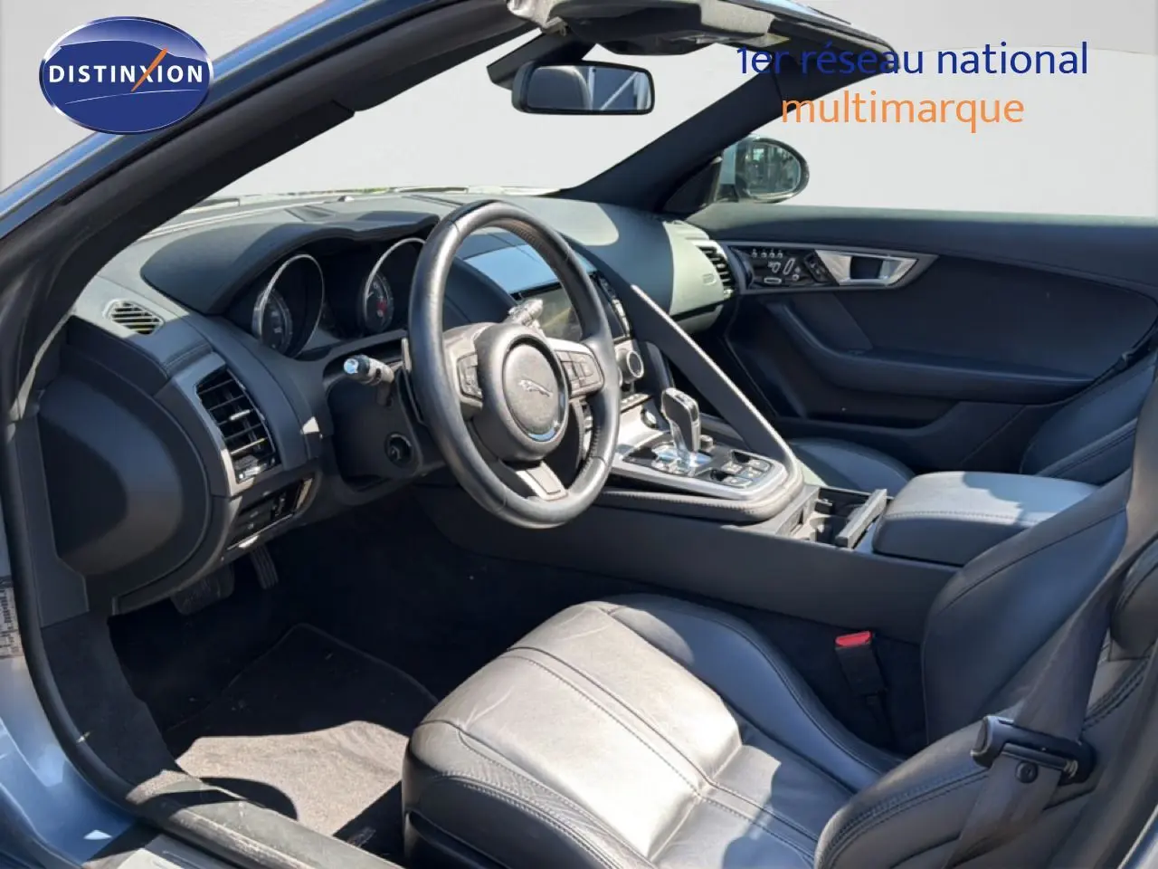 Vue intérieure côté conducteur de la Jaguar F-TYPE gris, mettant en valeur le volant cuir et la console centrale moderne.