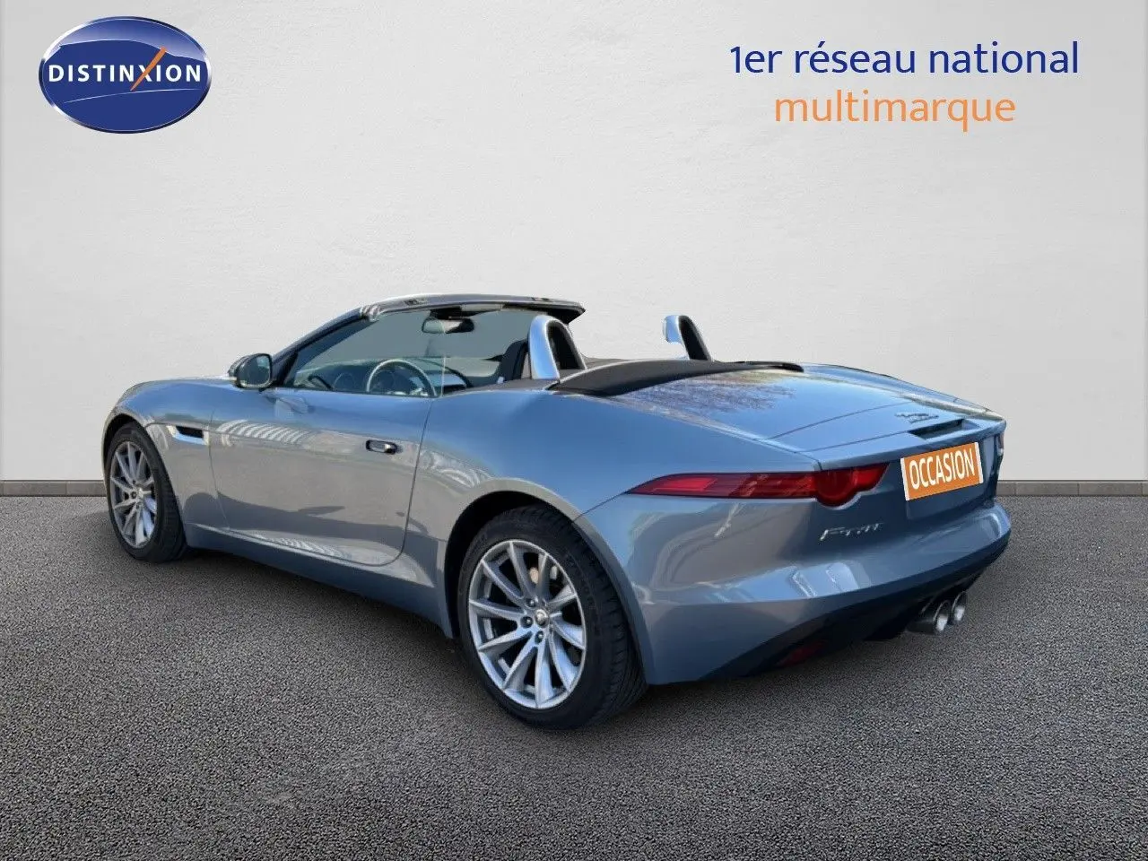 Jaguar F-TYPE cabriolet gris vue 3/4 arrière droit, toit ouvert et jantes alliage visibles.