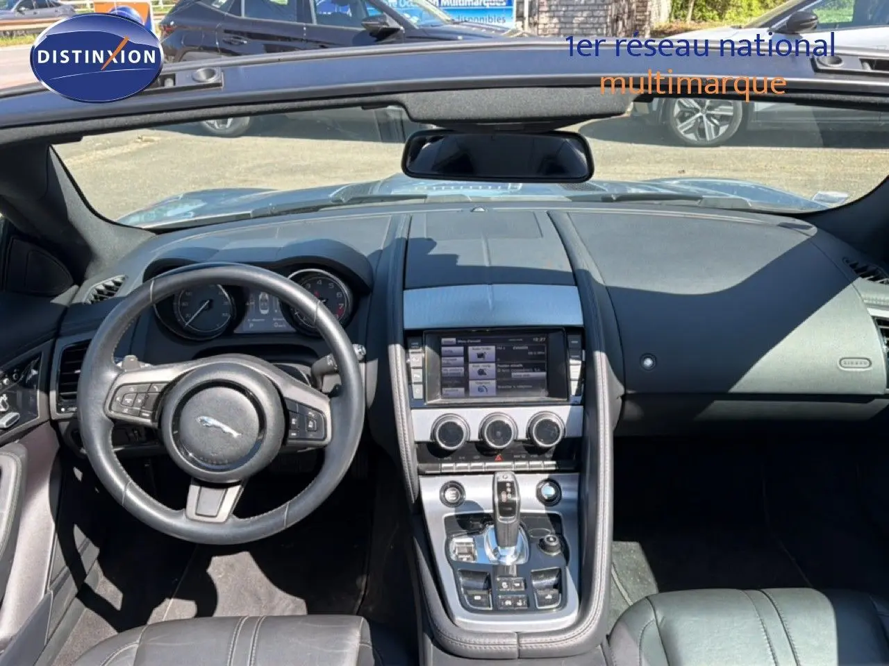 Vue intérieure avant de la Jaguar F-TYPE gris, tableau de bord avec écran tactile et volant cuir multifonctions.