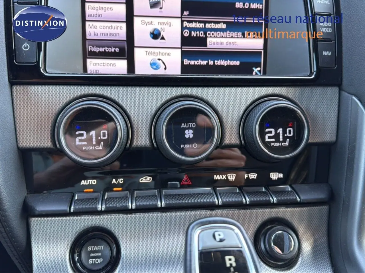 Gros plan sur la console centrale de la Jaguar F-TYPE gris, montrant les commandes de climatisation et le bouton start/stop.
