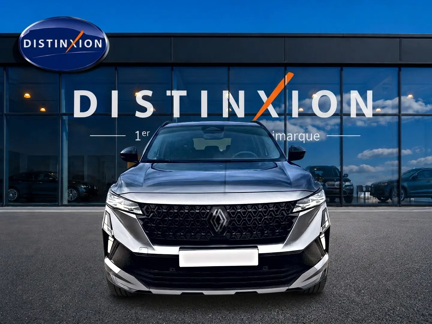 Vue frontale du Renault Austral gris schiste avec calandre noire et logo Renault bien visible, devant une vitrine Distinxion.