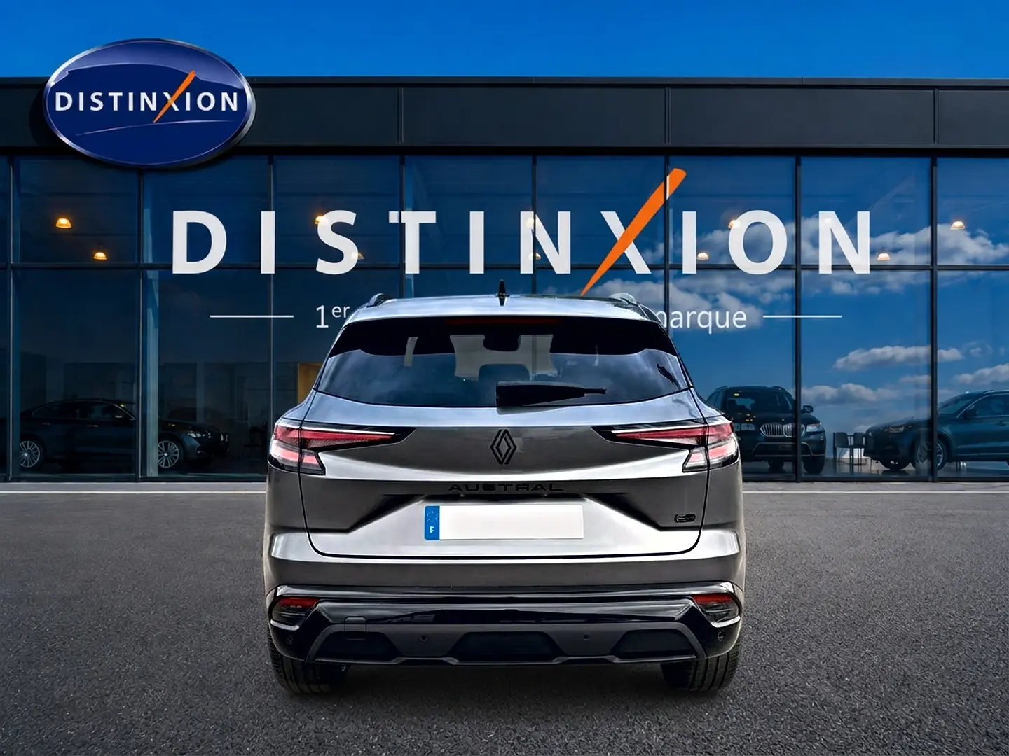 Vue arrière d'un Renault Austral gris schiste garé devant une vitrine avec logo Distinxion visible.